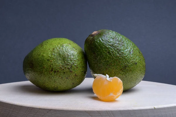 Abacate Verde Fatia Tangerina Uma Tábua Corte Fotografada Contra Fundo — Fotografia de Stock