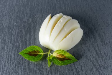 Haşlanmış yumurta, çiçek gibi kesilmiş ve gri arka planda yeşil yapraklar. 