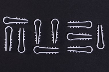 Elektrik kablosunu duvara bağlamak için beyaz plastik klipsler. Siyah arkaplanda teknolojik çivi yazısı