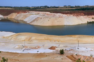 Büyük mavi bir göl kumlu bir taş ocağında farklı renklerde kumlarla