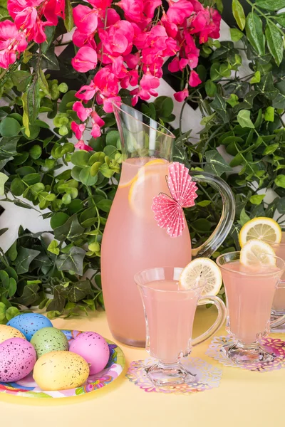 Садовий партійний стіл з глечиком та келихами рожевого лимонаду та великодніх яєць . — стокове фото