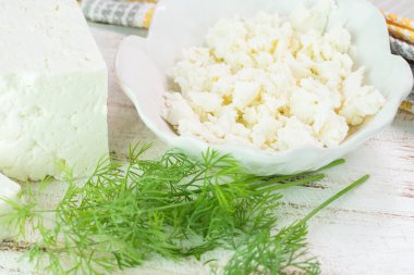 Taze beyaz peynir ve bir kesme tahtası üzerinde taze dereotu.