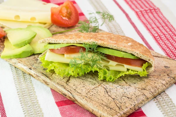 Pita pocket sandwich with cheese, avocado, tomato and lettuce. — Stock Photo, Image