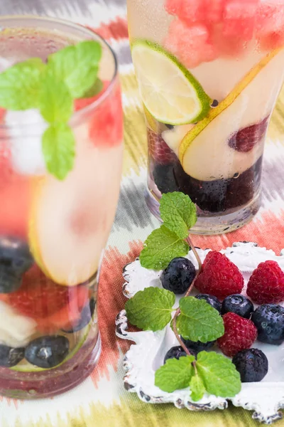 Gläser mit Früchten und Beeren, Wasser mit Minze und Eis. — Stockfoto