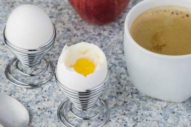 Fincan kahve ve iki haşlanmış yumurta yumurta içinde duruyor.