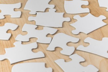 Düz beyaz jigsaw puzzle parçaları ahşap bir masa üzerinde.