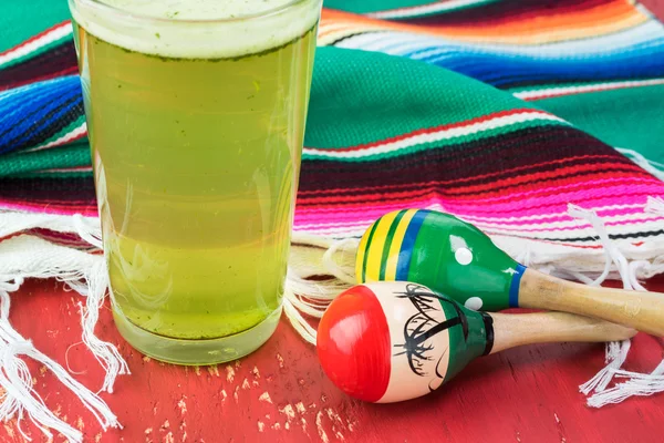 Pohár mész agua fresca, fiesta hagyomány fa maracas és színes asztali futó. — Stock Fotó