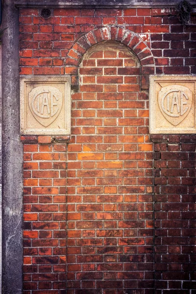 red brick wall with a sign of the facade of an old building.