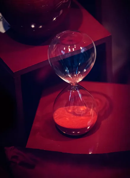 glass of red wine with a clock on a black background