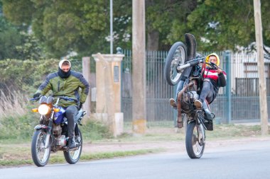 Motosikletçiler kırsal bir yolda tekerlek kullanıyorlar.