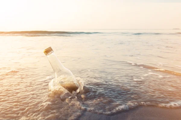 Botella en la playa con luz solar de lado, tono vintage — Foto de Stock