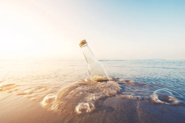 Пляшка на пляжі з сонячним світлом збоку, вінтажний тон — стокове фото