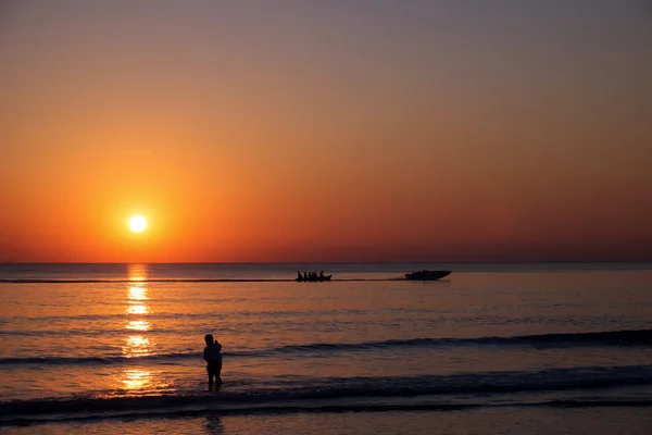 Vista do pôr do sol na praia com pessoas silhuetas — Fotografia de Stock
