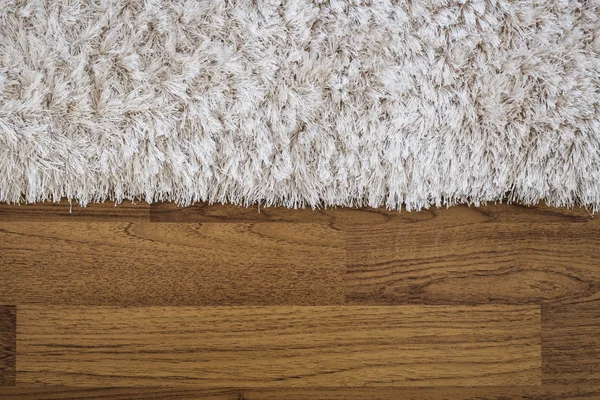 Zblízka nadýchané koberec na laminátové dřevěnou podlahu — Stock fotografie