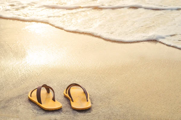 Chancla amarilla en la playa con luz brillante del atardecer en verano — Foto de Stock