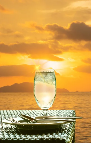 Vaso de agua fría sobre mesa de comedor al atardecer en la isla — Foto de Stock