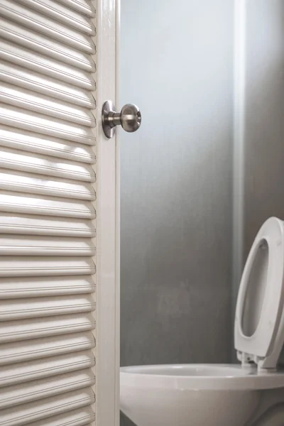 Fechar, abertura da porta do banheiro, com artigos de papelaria, foco seletivo na maçaneta da porta — Fotografia de Stock