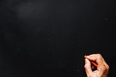 El tutma turuncu mum boya renk, yazı tahtası veya siyah kağıt ve kopya alanı üzerinde çizim