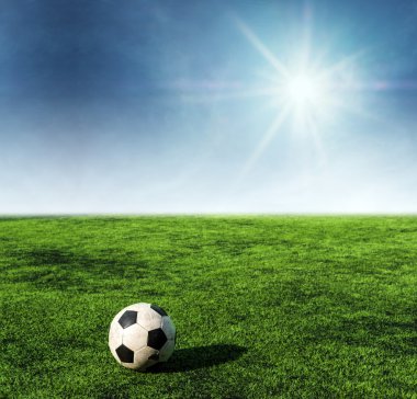 Mavi gökyüzü güneş üzerinde yeşil çim futbol sahası, futbol topu