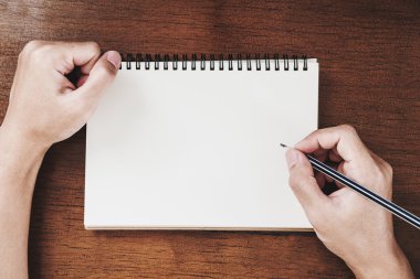 Defter ahşap masanın üzerinde vintage sesi yazılı kalem tutan el