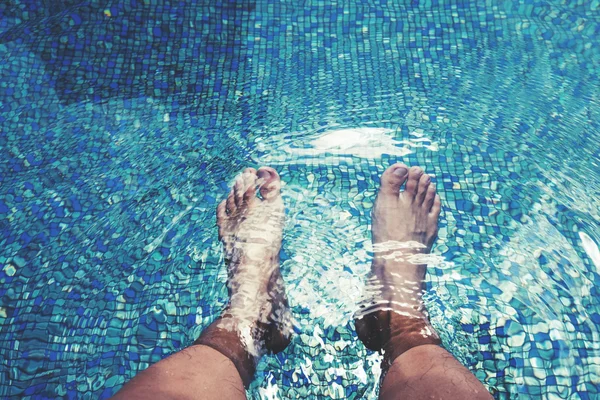 Pés masculinos com pele bronzeada, mergulhando na piscina — Fotografia de Stock