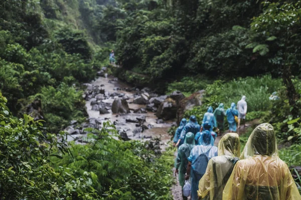 Люди в плащі, що йдуть в пагорбі в дощовий день, вибірковий фокус — стокове фото