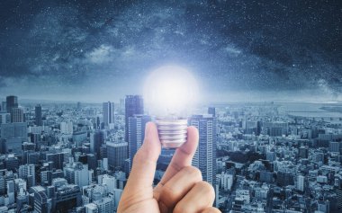 Fütürist şehir arka planına sahip, parlayan bir ampul.