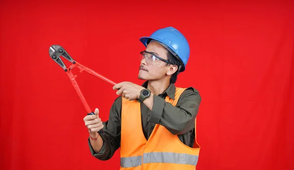 asian construction worker man wearing uniform, helmet, with cutter isolated red backgroubd