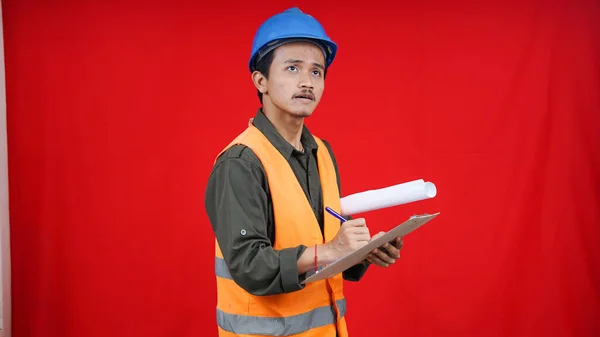 asian construction worker man wearing unifrom and helmet writting in paper isolated red background