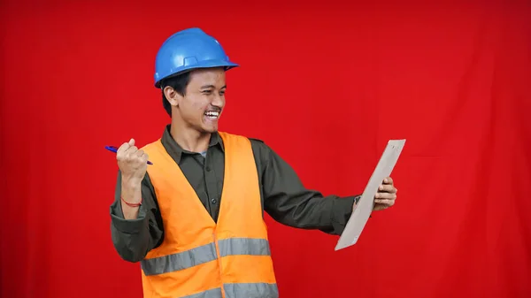 asian construction worker man wearing unifrom and helmet writting in paper isolated red background