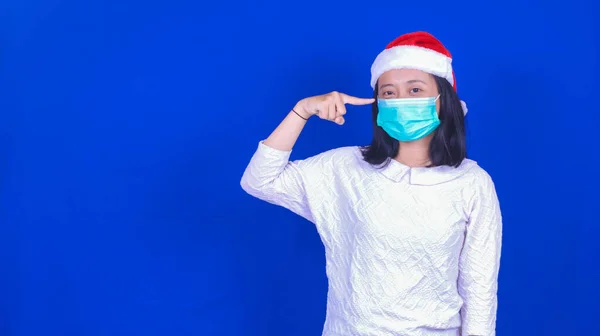 クリスマスの帽子とマスクを身に着けているアジアの女性は青の背景 — ストック写真