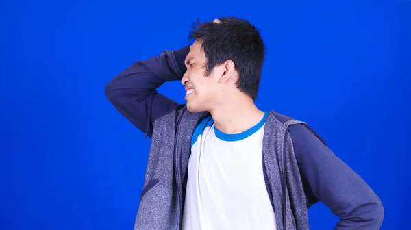 Azji Mężczyzna Nosić Ból Głowy Kurtka Odizolowany Niebieski Tło — Zdjęcie stockowe