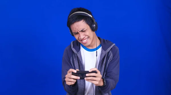 Asiatischer Mann Spielt Handyspiel Mit Glücklichem Gesichtsausdruck Isoliert Blauen Hintergrund — Stockfoto