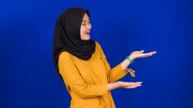 Asyalı kadın sağ boş alana işaret etti, izole edilmiş mavi arkaplan