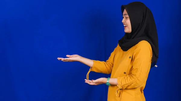 アジアの女性は空白のスペースを左に指摘青の背景を隔離 — ストック写真
