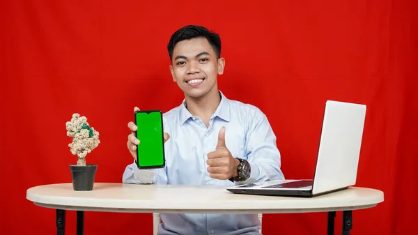 Молодой Азиатский Бизнесмен Указывая Зеленый Экран Телефона Изолированный Красный Фон — стоковое фото