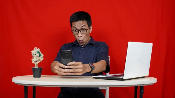 Genç Asyalı Adam Masadaki Akıllı Telefon Dizüstü Bilgisayarda Gördüklerini Görünce — Stok fotoğraf