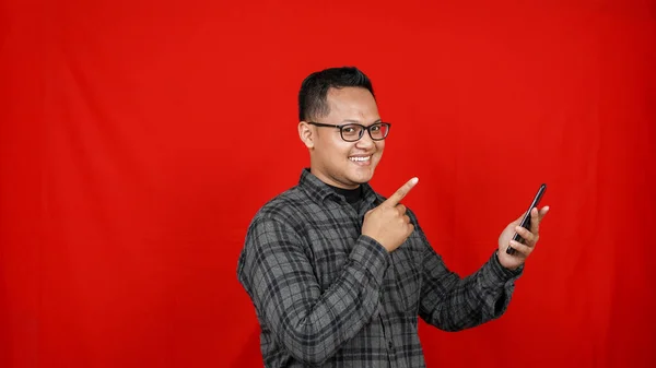 Wow face of Asian man shocked what he see in the smartphone isolated red background