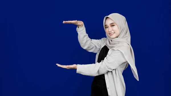 Asiatisk Hijab Kvinna Pekar Vänster Tomt Utrymme Isolerad Blå Bakgrund — Stockfoto