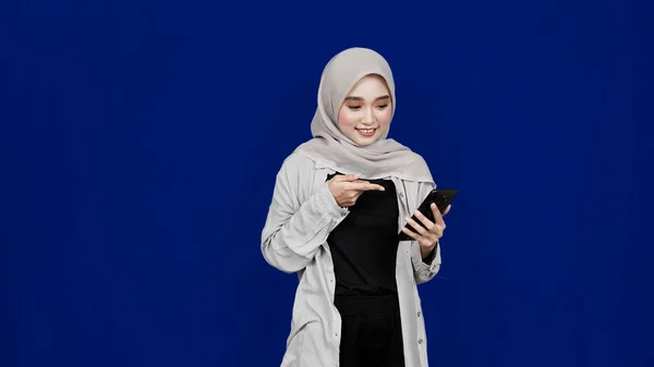 Asiatico Hijab Donna Che Punta Handphone Sorriso Espressione Isolato Blu — Foto Stock