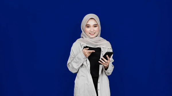 Asian Hijab Woman Pointing Handphone Smile Expression Isolated Blue Background — Stock Photo, Image