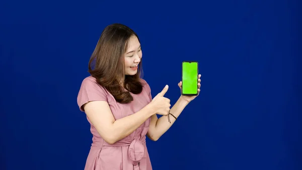 Piękny Azji Kobieta Wskazując Zielony Ekran Telefon Odizolowany Niebieski Tło — Zdjęcie stockowe