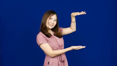 Asyalı kadın boşluğu işaret ediyor mavi arkaplan