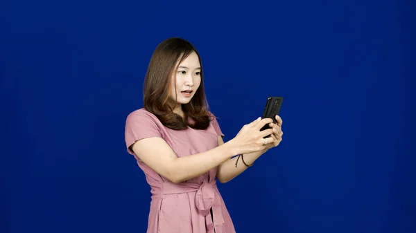 Asiático Mujer Sorprendida Expresión Ver Teléfono Aislado Azul Fondo —  Fotos de Stock