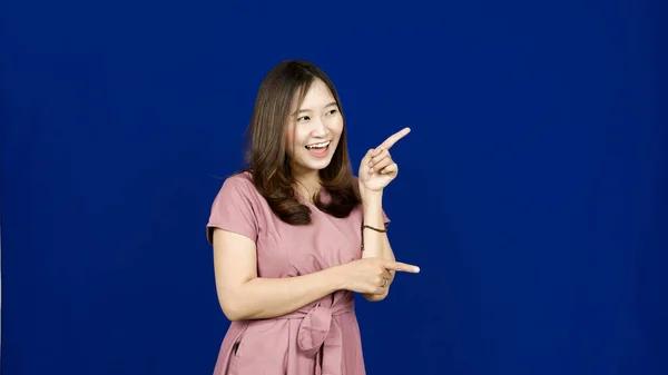 右の空白を指すアジアの女性隔離された青の背景 — ストック写真