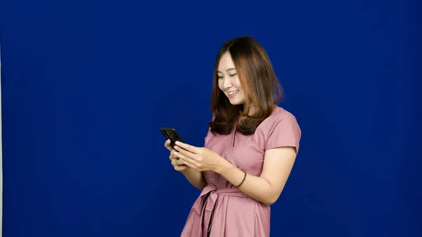 Piękny Azji Kobieta Uśmiech Zobacz Telefon Odizolowany Niebieski Tło — Zdjęcie stockowe