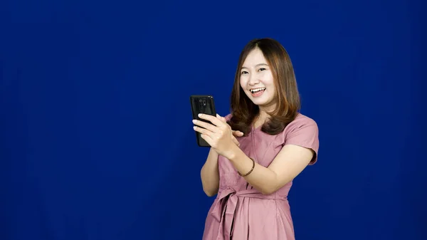 Portret Azjatki Wskazującej Swój Smartfon Odizolowanym Niebieskim Tle — Zdjęcie stockowe