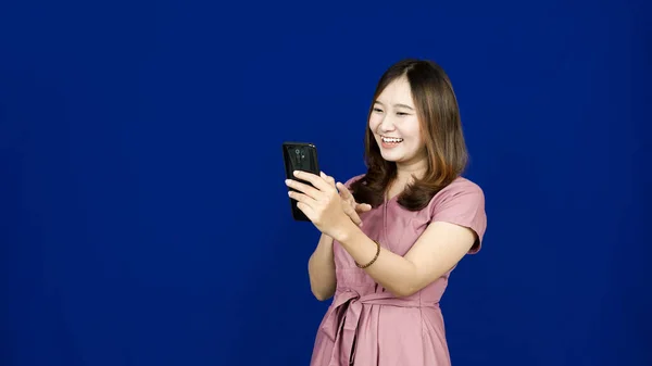 Portret Azjatki Wskazującej Swój Smartfon Odizolowanym Niebieskim Tle — Zdjęcie stockowe