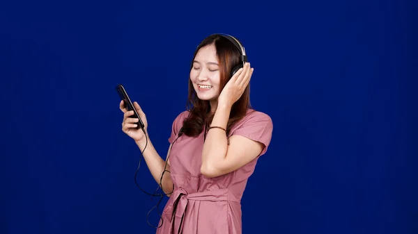 Asian Woman Listen Songs Using Headphones Isolated Blue Backg — Stock Photo, Image