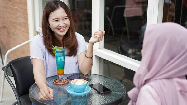 Asian woman talking and smimling with friend at cafe
